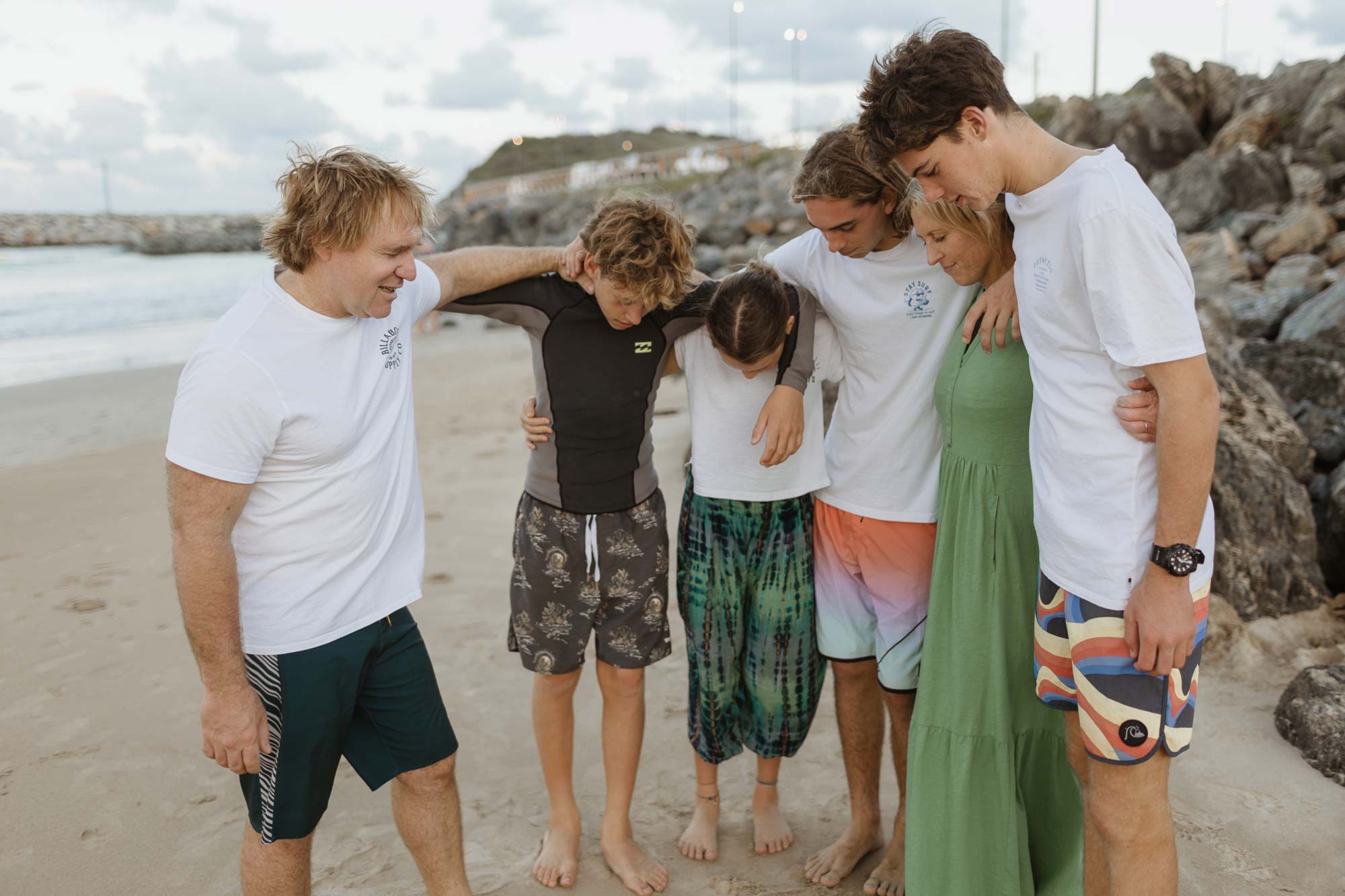 Family with teenage kids praying together on beach